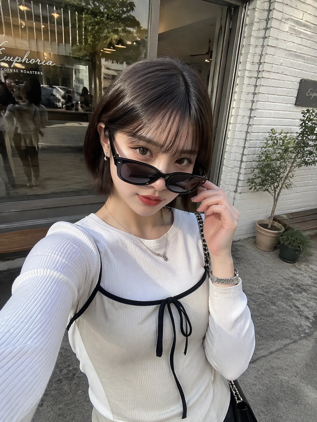 A young Japanese woman in her 20s took a selfie with an iPhone in front of a cafe…